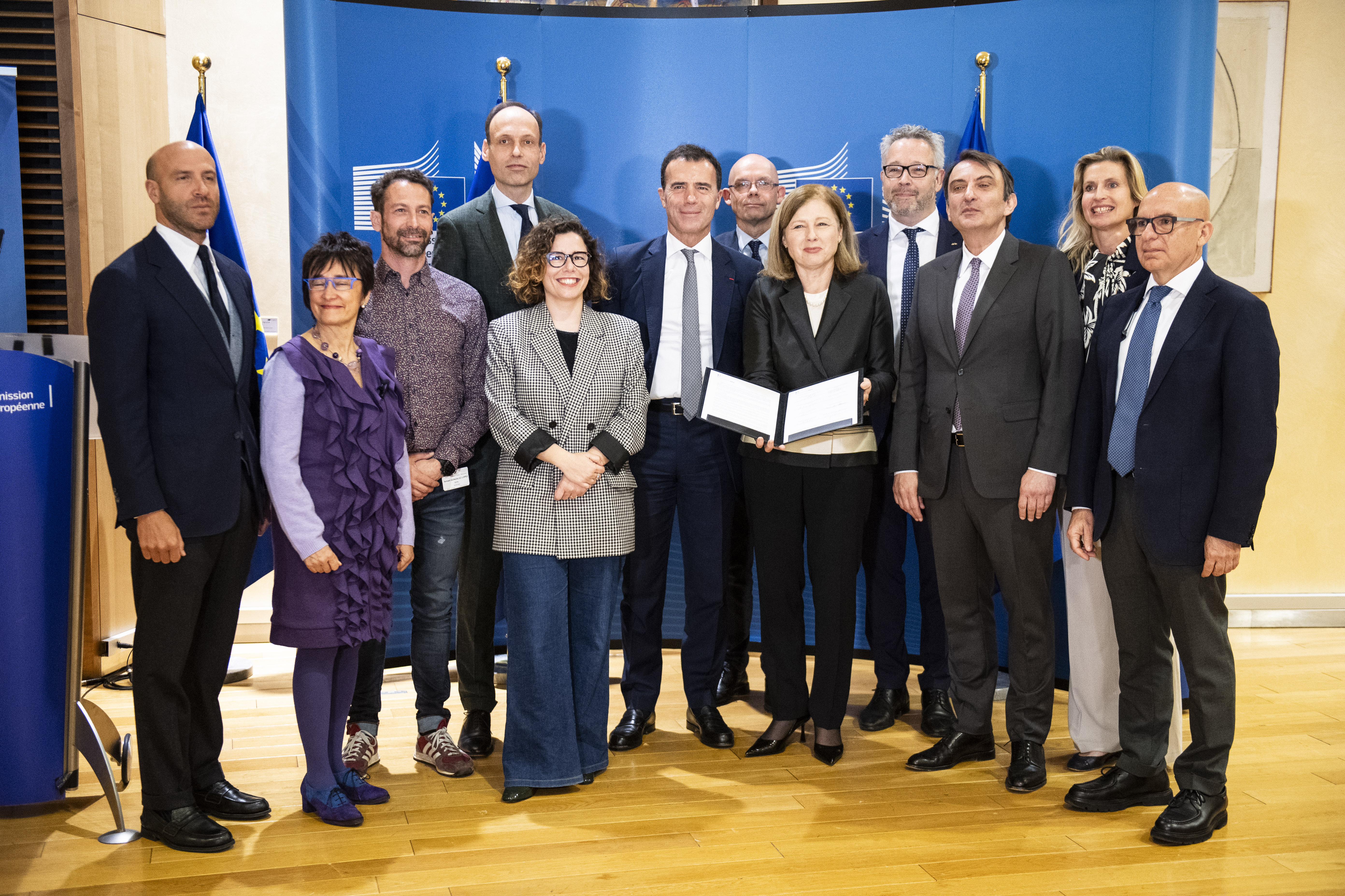 Officials from International IDEA and the European Commission pose for a photo with the leaders of several European political parties following the signing of a code of conduct at the headquarters of the European Commission in Brussels on 9 April 2024. Among the officials are International IDEA’s Director for Europe, Sam van der Staak, and Marilyn Neven, programme manager,  as well as European Commission Vice-President Vera Jourová (holding the signed document). Credit: European Union/Lukasz Kobus. 
